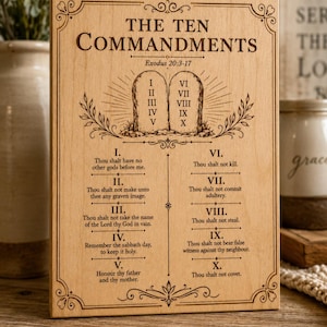 May include: A rectangular light-colored wooden plaque engraved with the text The Ten Commandments and Exodus 20:3-17. The design features two stone tablets with Roman numerals I through X, surrounded by decorative scrollwork and the full text of each.