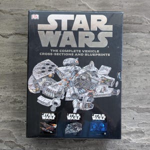 May include: A black book titled "STAR WARS" with the text "THE COMPLETE VEHICLE CROSS-SECTIONS AND BLUEPRINTS." The cover features detailed cross-section illustrations of Star Wars vehicles. Three smaller images of Star Wars vehicles are at the bottom.