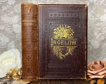 May include: Antique book with a brown leather cover. The spine reads "INGELOW'S POEMS" in gold lettering. The front cover features the name "INGELOW" in gold script, surrounded by floral and leaf designs. The book is a vintage literary item.
