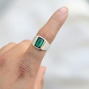 Könnte beinhalten: Ein silberner Ring mit einem rechteckigen grünen Edelstein.