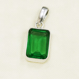 Puede incluir: Colgante rectangular de piedra verde con una fianza plateada. La piedra de talla esmeralda es de color verde vibrante y está engastada en un bisel plateado. El colgante está diseñado para un collar.