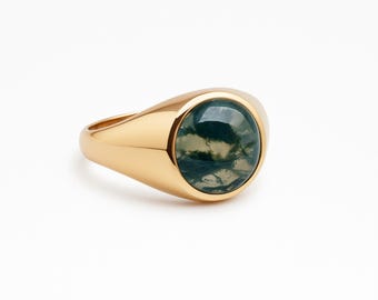 May include: A gold signet ring with a round, moss agate stone. The stone features green and white patterns. The ring has a polished finish and a classic, elegant design.