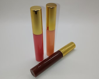 May include: Three tubes of lip gloss with gold caps. The lip glosses are in shades of brown, orange, and pink.