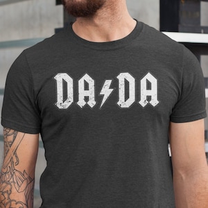 May include: A dark gray t-shirt with a white graphic that says "DA/DA" with a lightning bolt between the words.
