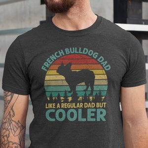 May include: A dark heather grey t-shirt with a vintage-style graphic of a French Bulldog. The graphic features a sunset with the text "French Bulldog Dad" and "Like a regular dad but cooler".