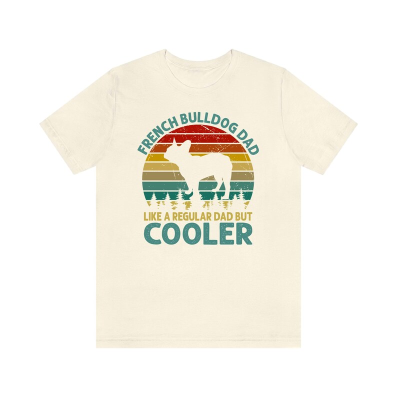 May include: A beige t-shirt with a vintage-style graphic of a French Bulldog. The graphic says "French Bulldog Dad Like a Regular Dad But Cooler".