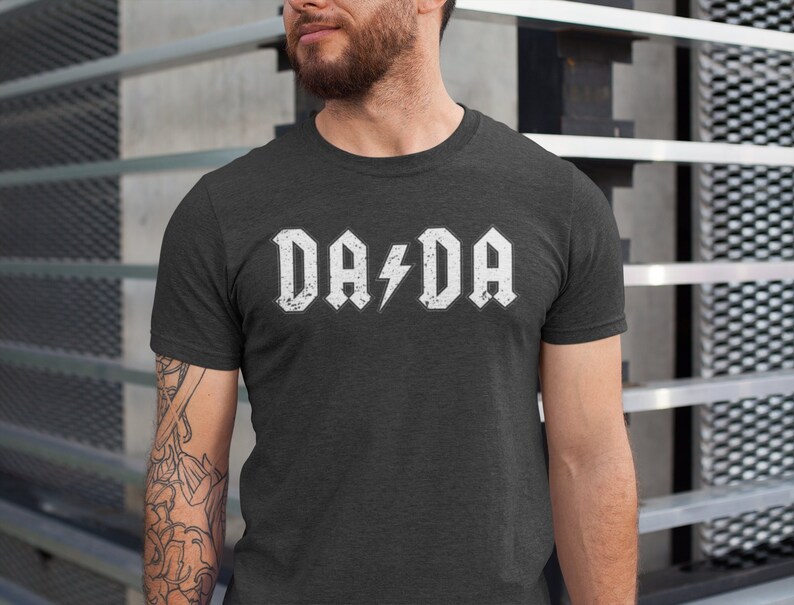 May include: A dark gray t-shirt with a white graphic that says "DA/DA" with a lightning bolt between the words.