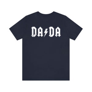 May include: A navy blue t-shirt with a white distressed graphic that says "DA DA" with a lightning bolt in between the words.
