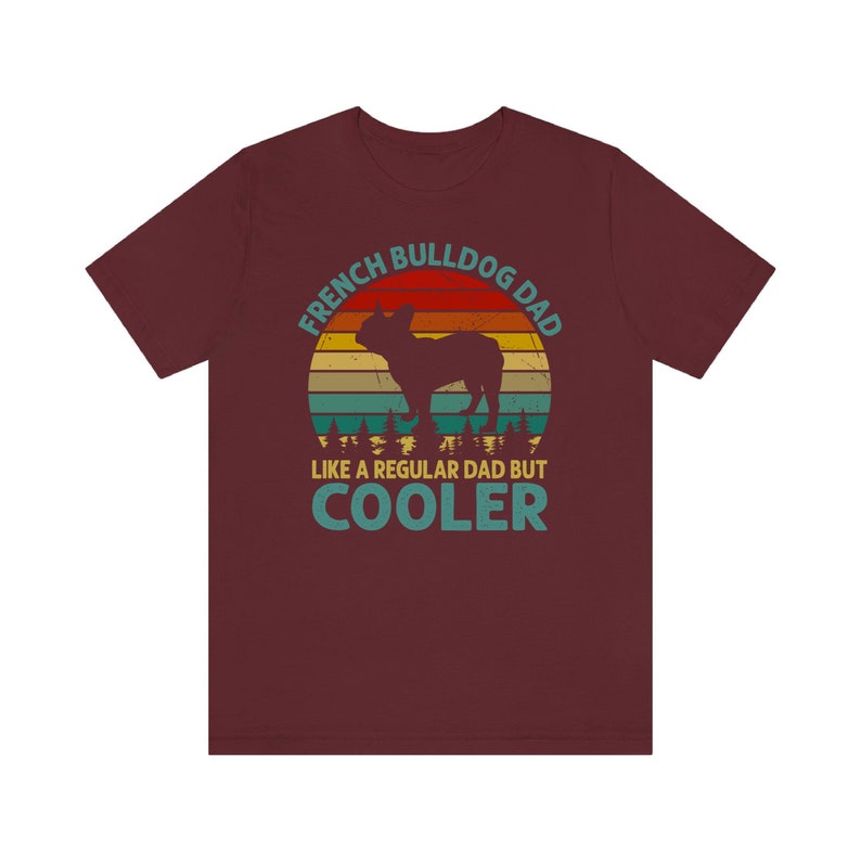 May include: A maroon t-shirt with a vintage-style graphic of a French Bulldog. The graphic says "French Bulldog Dad Like a Regular Dad But Cooler".