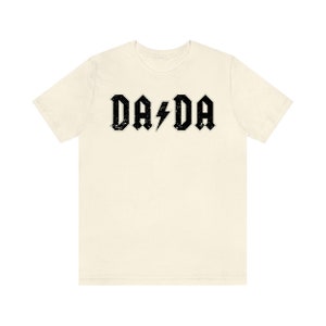 May include: A cream colored t-shirt with a black graphic that says "DA DA" with a lightning bolt in between the words.