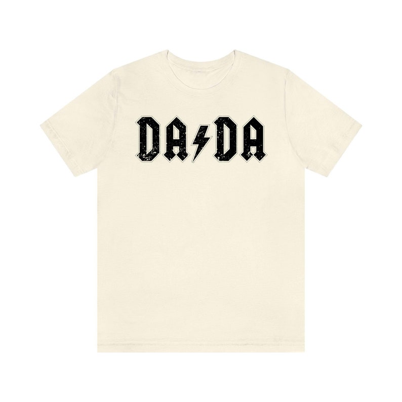 May include: A cream colored t-shirt with a black graphic that says "DA DA" with a lightning bolt in between the words.