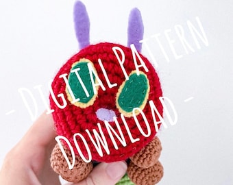 May include: A crocheted stuffed toy of the very hungry caterpillar. The caterpillar is red with green spots and purple antennas. The body is green and brown.