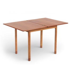 May include: A rectangular wooden table with a light brown finish. The table has four legs and a two-piece top that appears to fold open. The table is approximately 30 inches long and 24 inches wide.