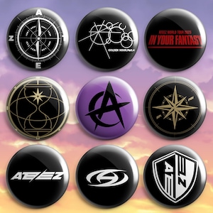 Pode incluir: Um conjunto de nove botões redondos com vários designs gráficos. Os botões exibem símbolos incluindo uma bússola, uma ampulheta, o texto ATEEZ WORLD TOUR 2025 IN YOUR FANTASY, GOLDEN HOUR:Part.4 e logótipos estilizados em preto, branco, dourado e roxo.
