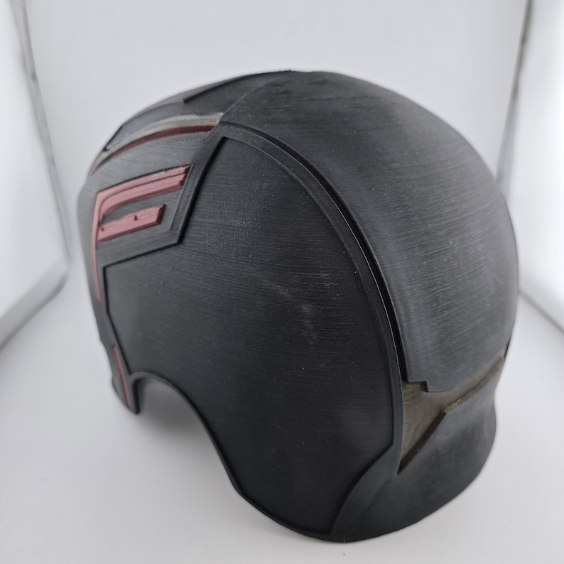May include: Black plastic helmet with a red and silver star design. The helmet is a prop for cosplay or costume.