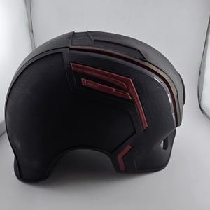 May include: A black helmet with red accents. The helmet has a smooth, rounded surface and a slightly pointed top.