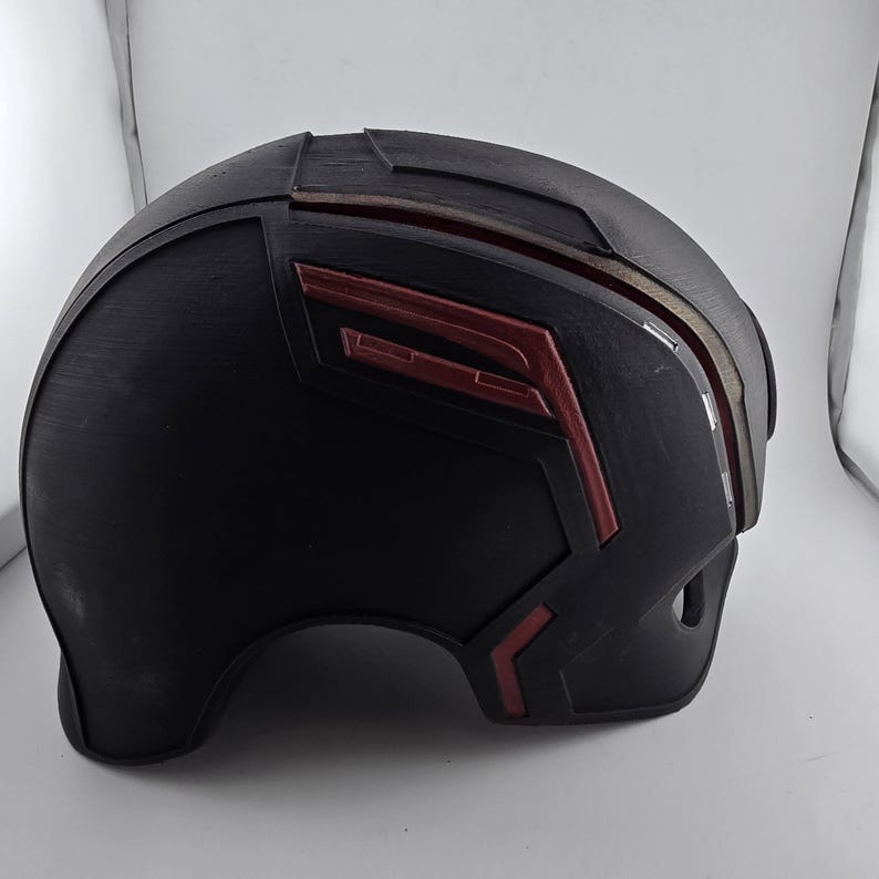 May include: A black helmet with red accents. The helmet has a smooth, rounded surface and a slightly pointed top.