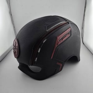 May include: Black helmet with red and white accents. The helmet has a red and white design on the side and a black and white symbol on the front.