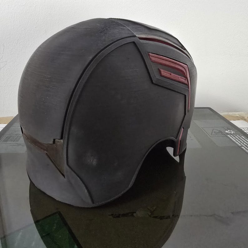May include: A black helmet with red accents. The helmet has a smooth, rounded surface and a slightly pointed top. The red accents are in the shape of a stylised letter "F".