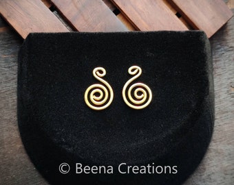 May include: A pair of gold-colored earrings with a spiral design. The earrings are on a black velvet background.