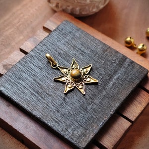 May include: Gold pendant with a tiger's eye gemstone in the center, surrounded by a detailed floral design.