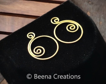 May include: A pair of gold-colored wire earrings with a spiral design. The earrings are on a black background.