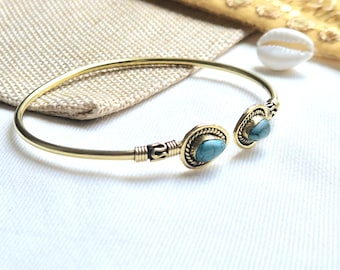 May include: A gold bangle bracelet with two turquoise stones set in ornate metal settings.