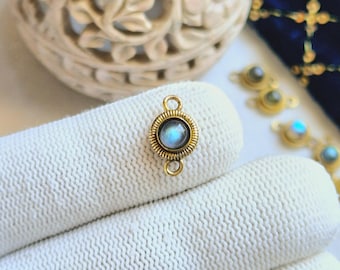 May include: Gold-toned connector with a round, iridescent blue gemstone. The connector has two loops for attaching jewelry.