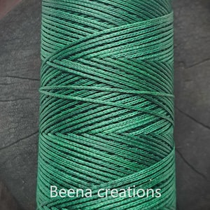 May include: A spool of dark green thread, wound tightly. The thread is smooth and has a slight sheen. The spool is labeled "Beena creations".