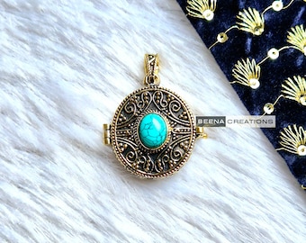 May include: A gold-toned pendant with a turquoise stone set in a circular filigree design. The pendant has a hinged opening.