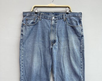 May include: A pair of light blue denim jeans hanging on a wooden hanger. The jeans have a classic five-pocket style and a straight leg.