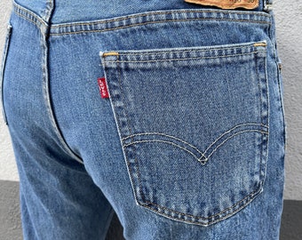 May include: A pair of blue denim jeans with a brown leather Levi's patch on the back pocket. The patch has the Levi's logo and the text "Levi Strauss & Co. San Francisco, Cal. Original  Quality  Clothing  517" W36 L30.