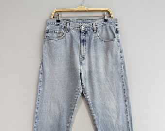 May include: Light blue denim jeans hanging on a wooden hanger. The jeans have a classic straight leg style and a faded wash.