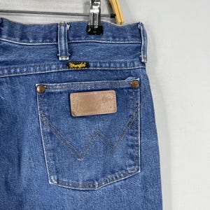 May include: A pair of blue denim jeans with a brown leather patch that says "Wrangler" on the back pocket.