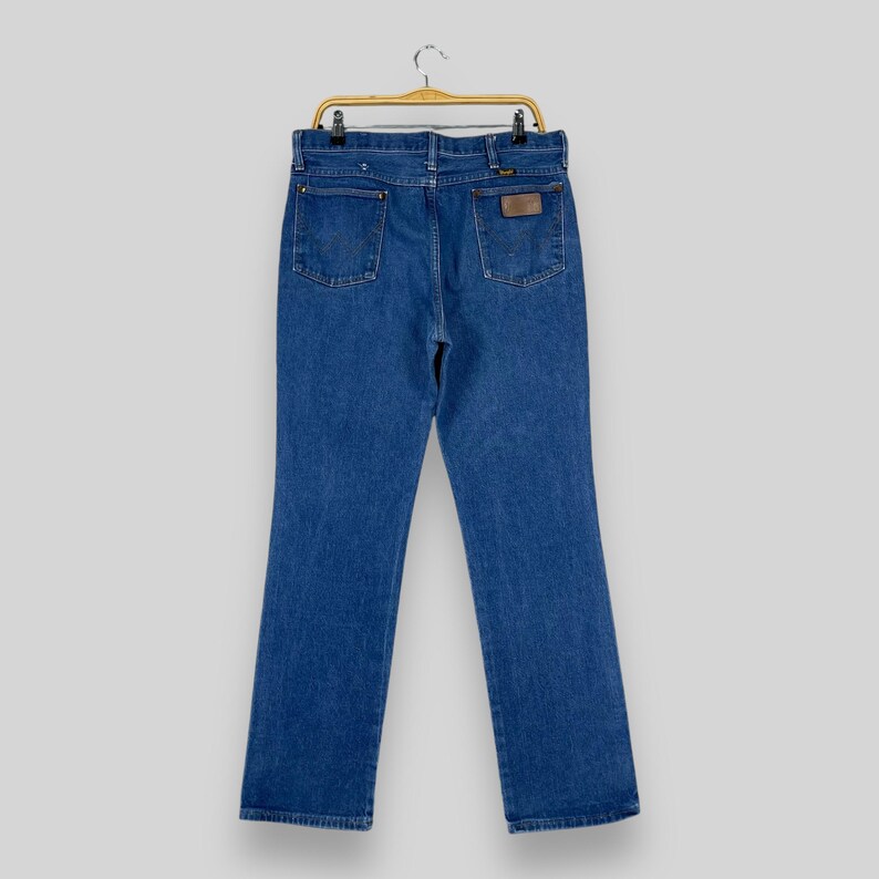 May include: A pair of blue denim jeans with a brown leather patch on the back pocket.