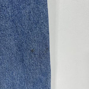 K&ouml;nnte beinhalten: Nahaufnahme eines blauen Jeansstoffs mit einer subtilen Textur. Der Stoff hat einen leichten Glanz und wirkt weich.