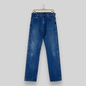 May include: A pair of blue denim jeans hanging on a wooden hanger. The jeans have a classic straight leg style and are made of a durable cotton blend.