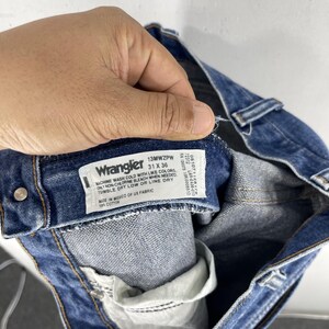 May include: Blue denim jeans with a Wrangler label that reads "13MWZPW 31 X 36" and includes care instructions. The label is attached to the inside of the waistband.