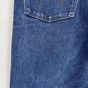 K&ouml;nnte beinhalten: Nahaufnahme von blauem Jeansstoff mit einer einzigen Ges&auml;&szlig;tasche. Die Tasche hat einen gen&auml;hten Rand und eine dezente, ausgewaschene Optik.