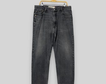 May include: A pair of dark gray denim jeans hanging on a gold hanger. The jeans have a straight leg and a classic five-pocket design.