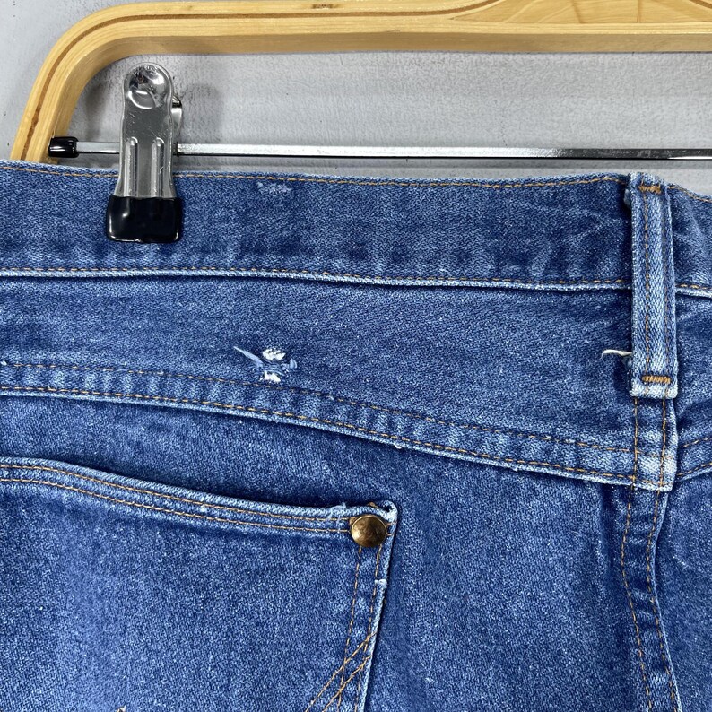 May include: A pair of blue denim jeans with a single back pocket and a visible seam along the back waistband.