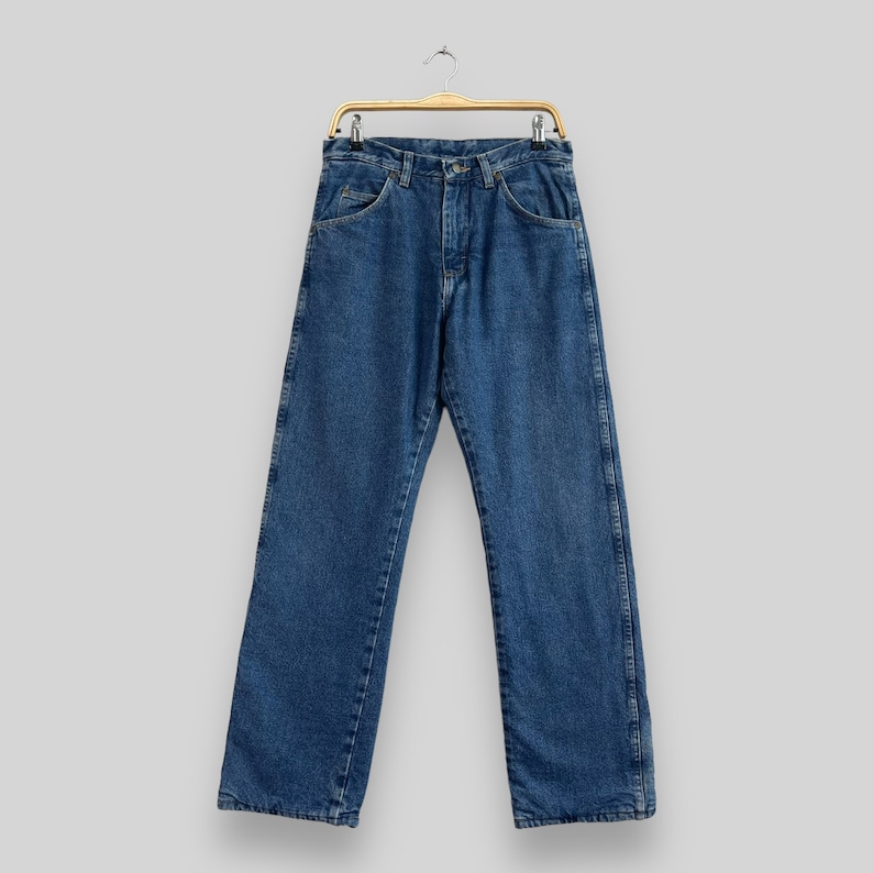 May include: A pair of blue denim jeans hanging on a wooden hanger. The jeans have a classic straight leg style and are made of a soft, comfortable fabric.