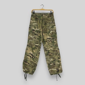 Könnte beinhalten: Camouflage-Cargohose mit einem Kordelzug am unteren Ende jedes Beins. Die Hose hängt an einem Holzbügel.