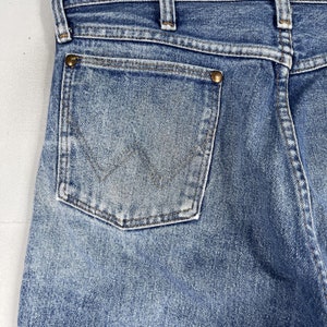 May include: A pair of blue denim jeans with a back pocket featuring a stitched 'W' logo and a copper rivet.
