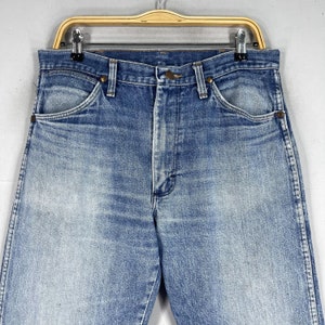 May include: A pair of light blue denim jeans with a faded look. The jeans have a classic five-pocket style and a straight leg.
