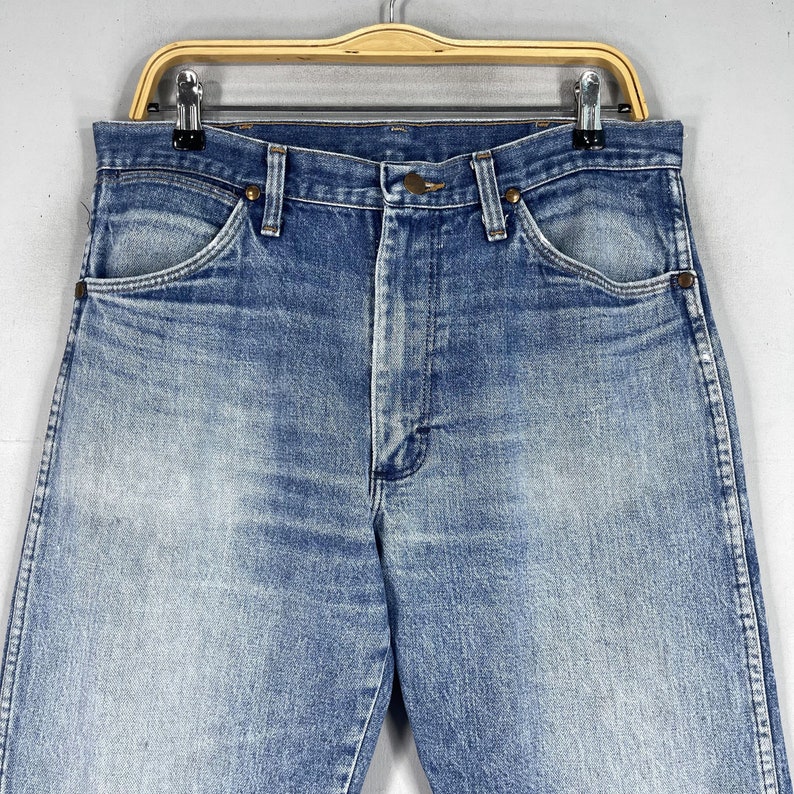 May include: A pair of light blue denim jeans with a faded look. The jeans have a classic five-pocket style and a straight leg.