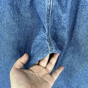 K&ouml;nnte beinhalten: Nahaufnahme von blauem Jeansstoff mit einer Naht, die in der Mitte verl&auml;uft. Der Stoff ist strukturiert und hat einen leicht verblassten Look.