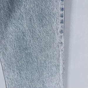 Pode incluir: Close-up da textura de um tecido de ganga azul claro. O tecido tem um padr&atilde;o de trama diagonal.