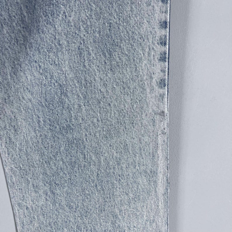 Pode incluir: Close-up da textura de um tecido de ganga azul claro. O tecido tem um padr&atilde;o de trama diagonal.