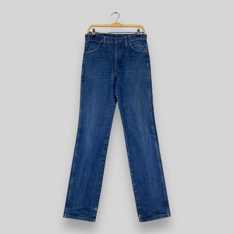 K&ouml;nnte beinhalten: Eine blaue Jeans aus Denim, die an einem Holzb&uuml;gel h&auml;ngt. Die Jeans hat einen klassischen geraden Schnitt und ist aus strapazierf&auml;higem Baumwollgemisch gefertigt.